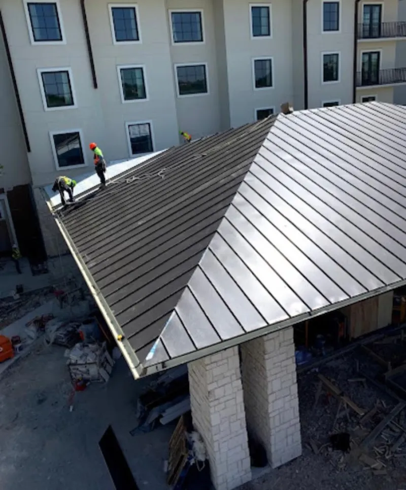 Crew installing standing seam metal roof panels on a commercial project in Chaska